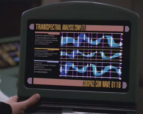 A retro-futuristic computer from Star Trek with three waveforms overlaid on grids. The top left reads "TRANSPECTRAL ANALYSIS COMPLETE", and the bottom right reads "SUBSPACE COM WAVE 0118". There some small, illegible text to the left of the wave forms.