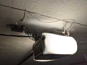 Mounted case with wires attached to garage door opener