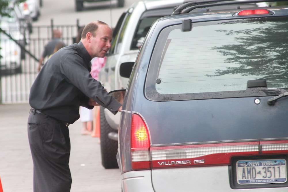 <b>Move-in 2009 welcome - 2</b><br /> Closeup of Father Pilarz greeting an incoming freshman and their family as they arrive on campus in their vehicle in 2009.