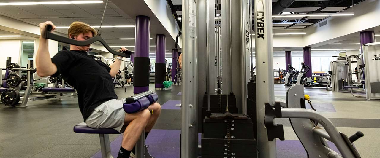  Male student working out on an arm machine in the Fitness Center.