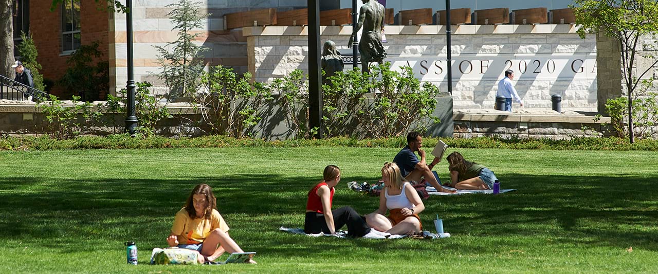  Students sitting on blankets on the grass on a sunny spring day.