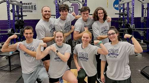 Group posing in the University fitness center and wearing T-shirts bearing a University Fitness Challenge logo
