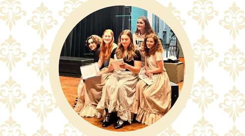 photo of people on a theatre stage set on background of fleur de lis pattern